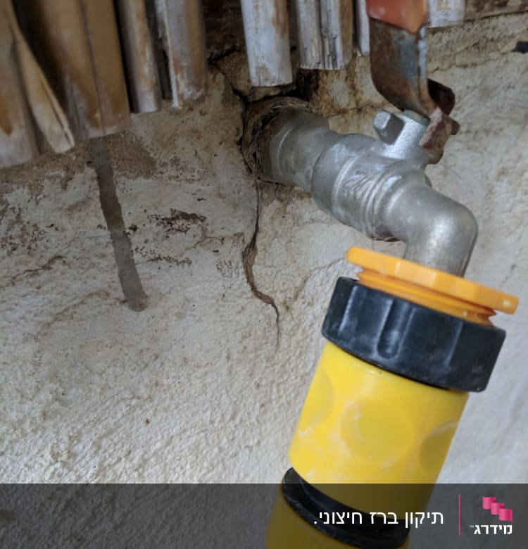 ברז מתכת עם צינור מחובר בקיר